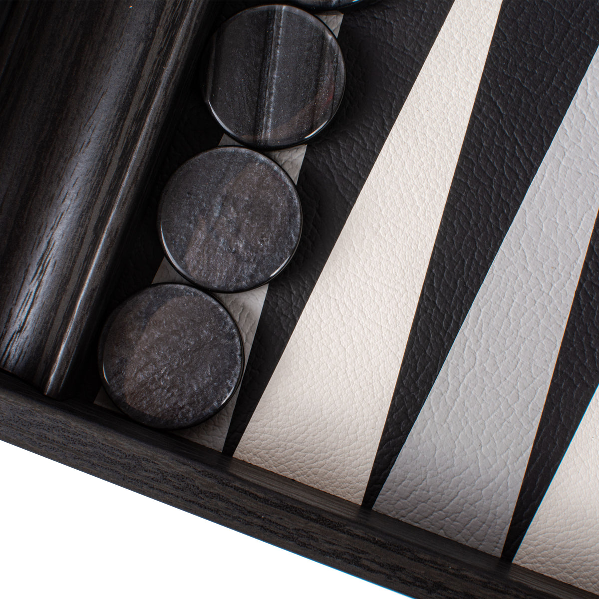 Close-up of a black leatherette backgammon board with dark round playing pieces and a rich wood frame by Manopoulos Chess and Backgammon
