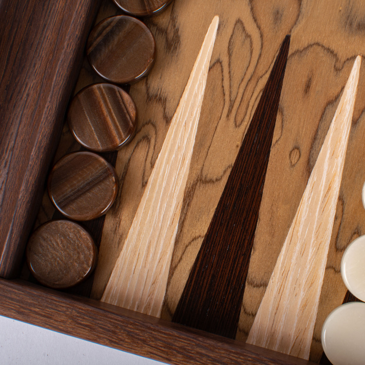 Close view of a handcrafted walnut burl backgammon board with dark wooden checkers and contrasting inlaid points by MANOPOULOS Chess & Backgammon