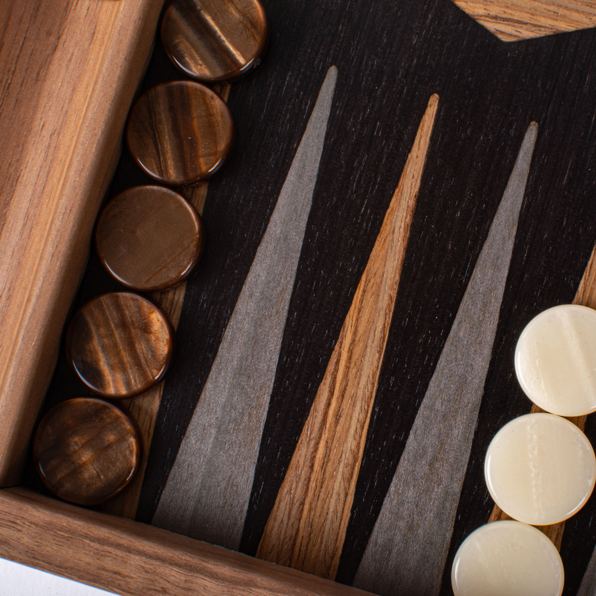 Close up of a handcrafted walnut and black oak backgammon board with rich wood grain and brown and ivory playing pieces by Manopoulos Greek craftsmanship