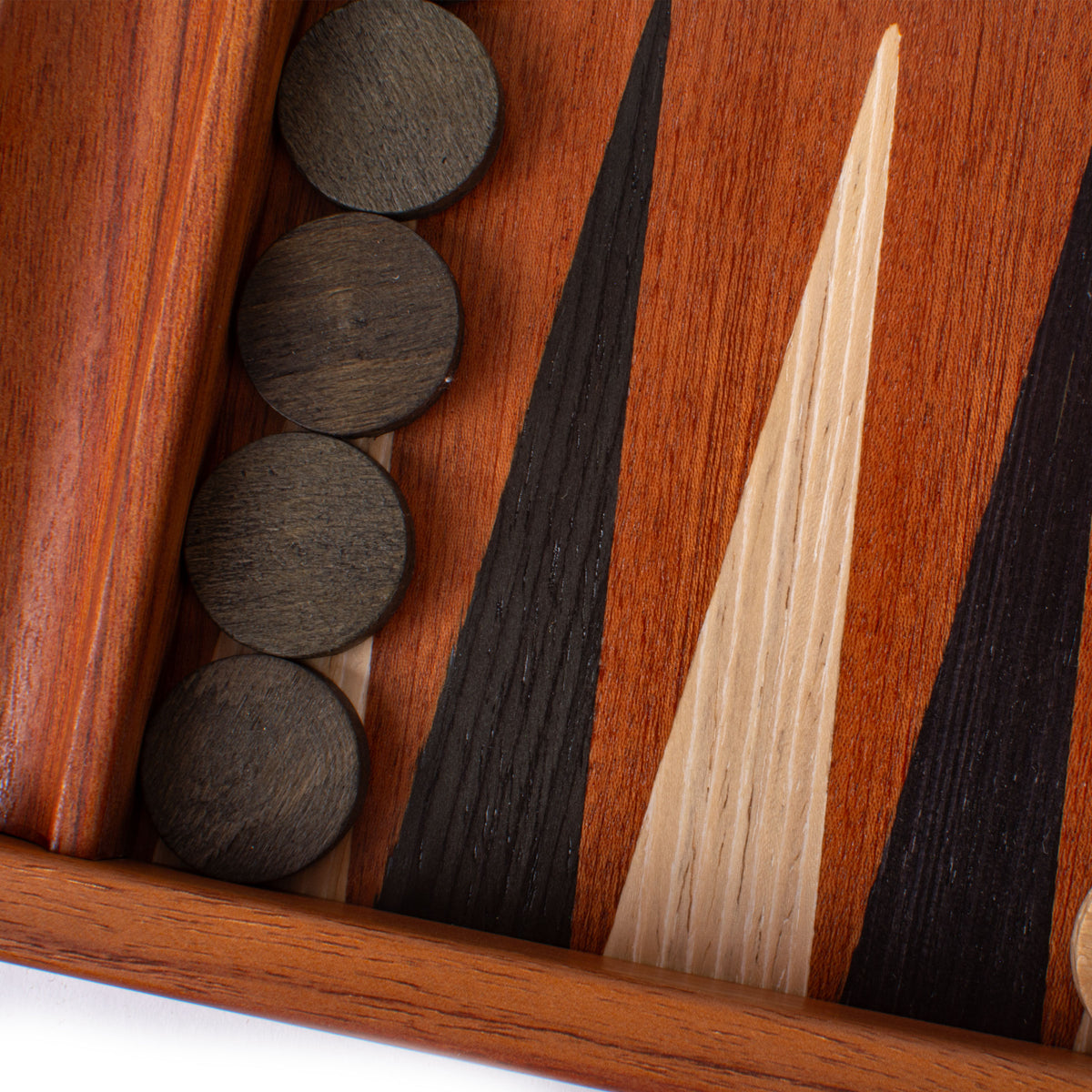 Close up of a mahogany backgammon board with bold marquetry inlays and dark playing pieces in a side rack by MANOPOULOS Chess and Backgammon