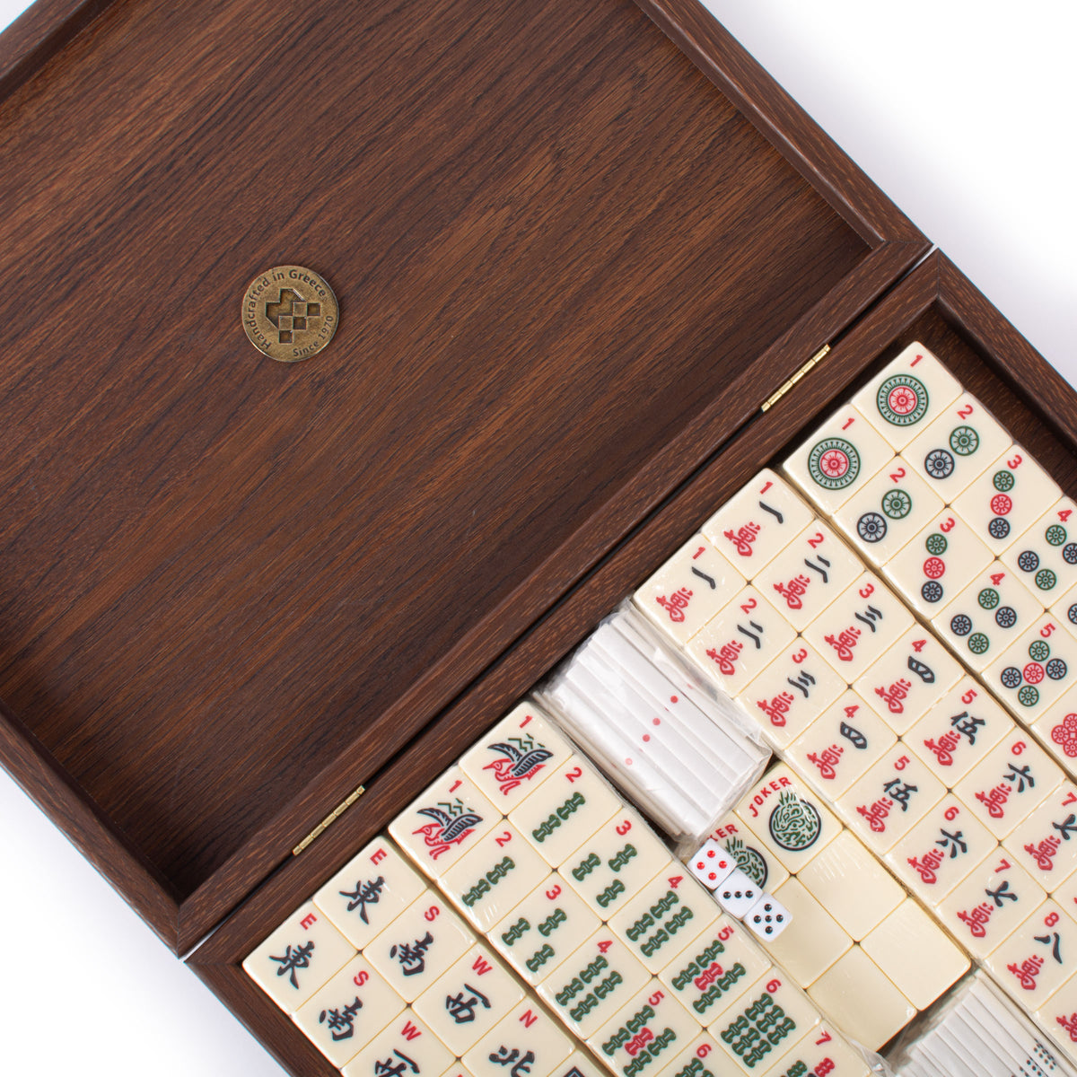 Premium Mahjong tiles arranged in a dark brown wooden case with ornate traditional symbols and colorful details from MANOPOULOS Chess and Backgammon