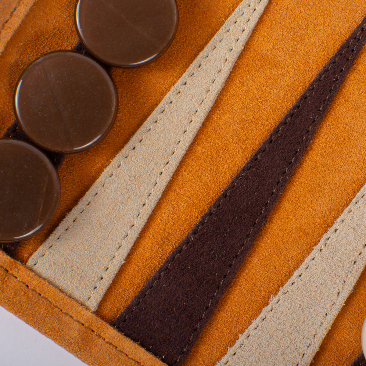 Close-up of a cinnamon brown suede backgammon board with dark checkers and contrasting stitched leather playing points by MANOPOULOS Chess and Backgammon