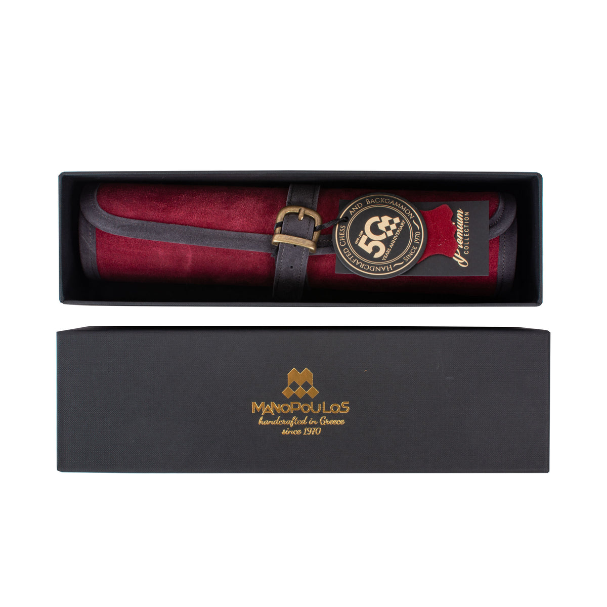 Red leather game accessory with a strap and decorative medallion displayed in an open black presentation box beside a matching Manopoulos box