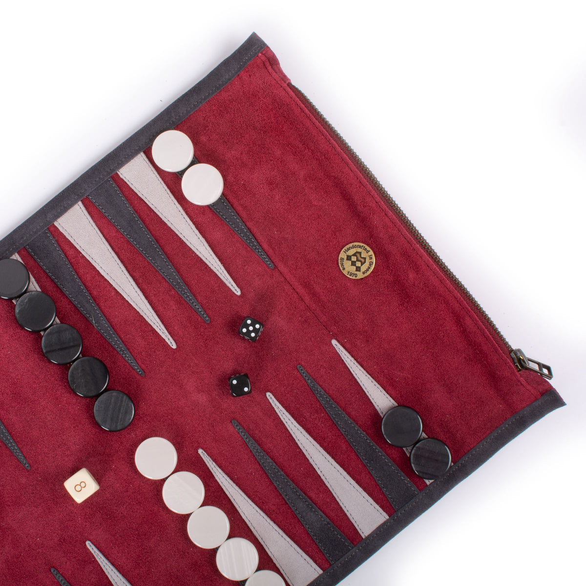 Open red felt backgammon board with black and white checkers, two dice, and a doubling cube arranged across pointed playing spaces