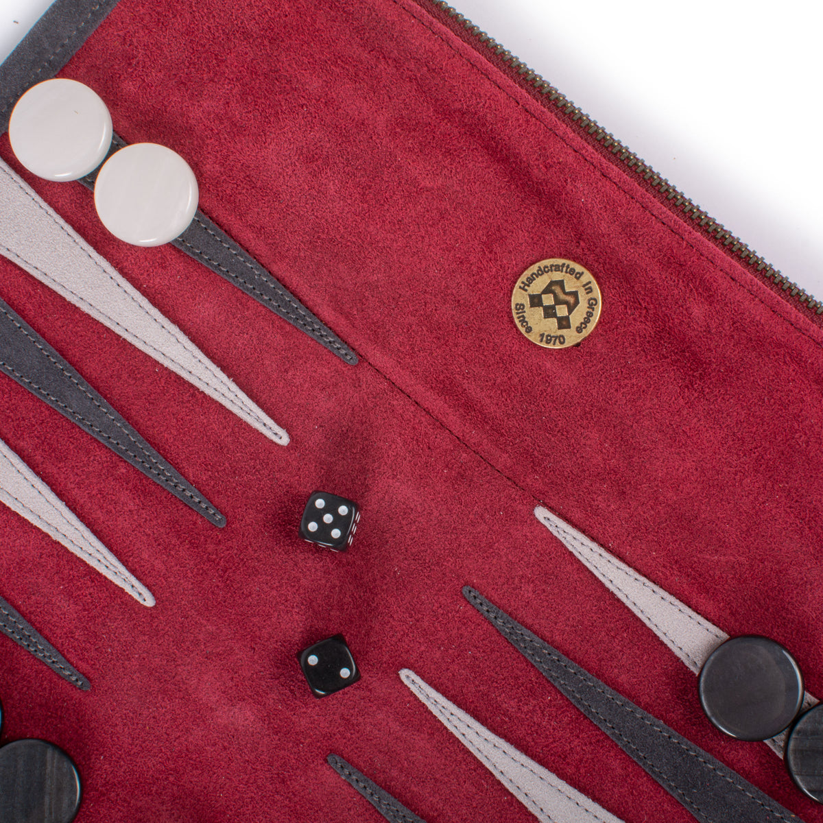 Close-up of a red backgammon board with white and black playing pieces, two dice, and contrasting pointed spaces in a rich textured finish.