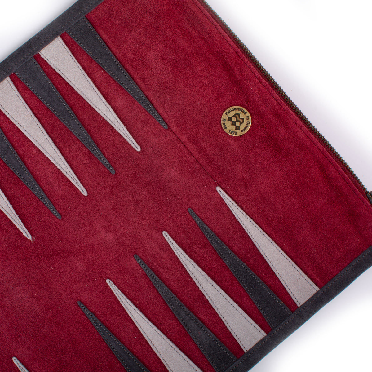 Red backgammon board interior with rich crimson felt alternating black and white points and a small round decorative emblem near the center panel