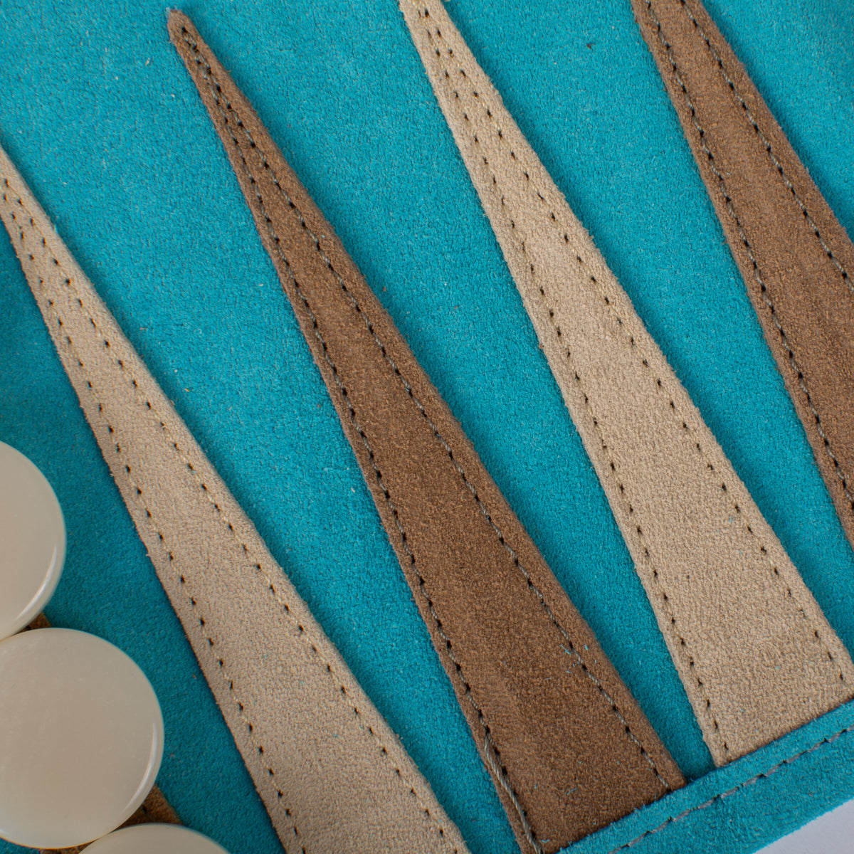 Close-up of a turquoise suede roll-up backgammon board with alternating stitched tan and brown panels from MANOPOULOS Chess and Backgammon