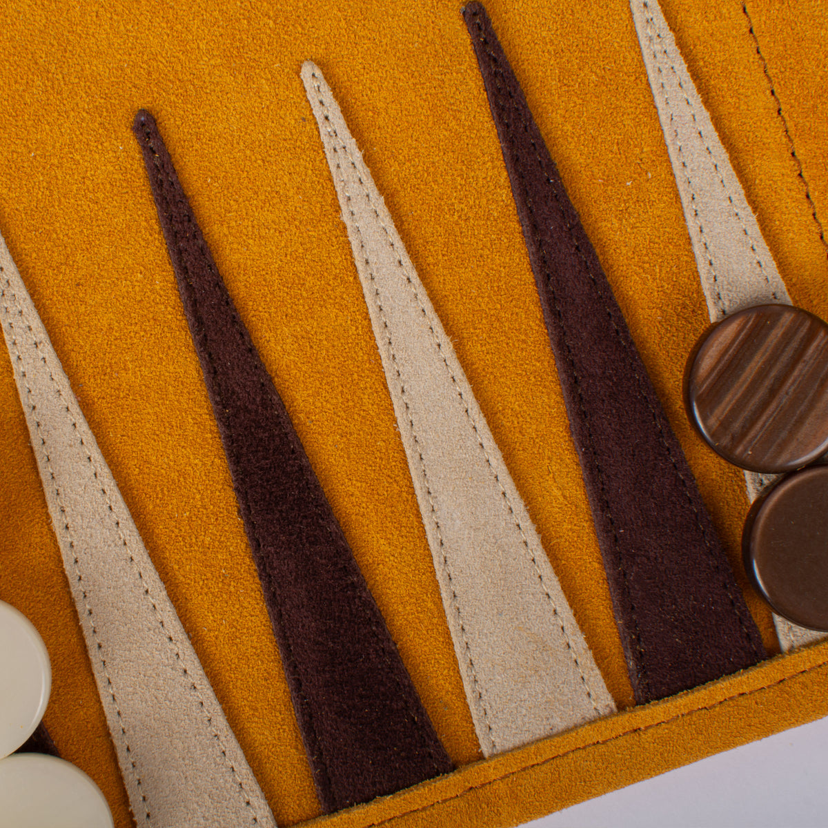 Close up of a warm yellow suede backgammon board with brown and cream points and wooden playing pieces by MANOPOULOS Chess & Backgammon