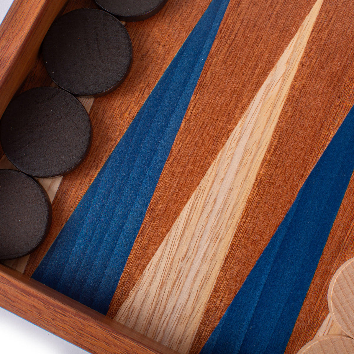 Close up of a handcrafted mahogany backgammon board with blue marquetry accents and dark wooden checkers showcasing Greek craftsmanship and luxury design
