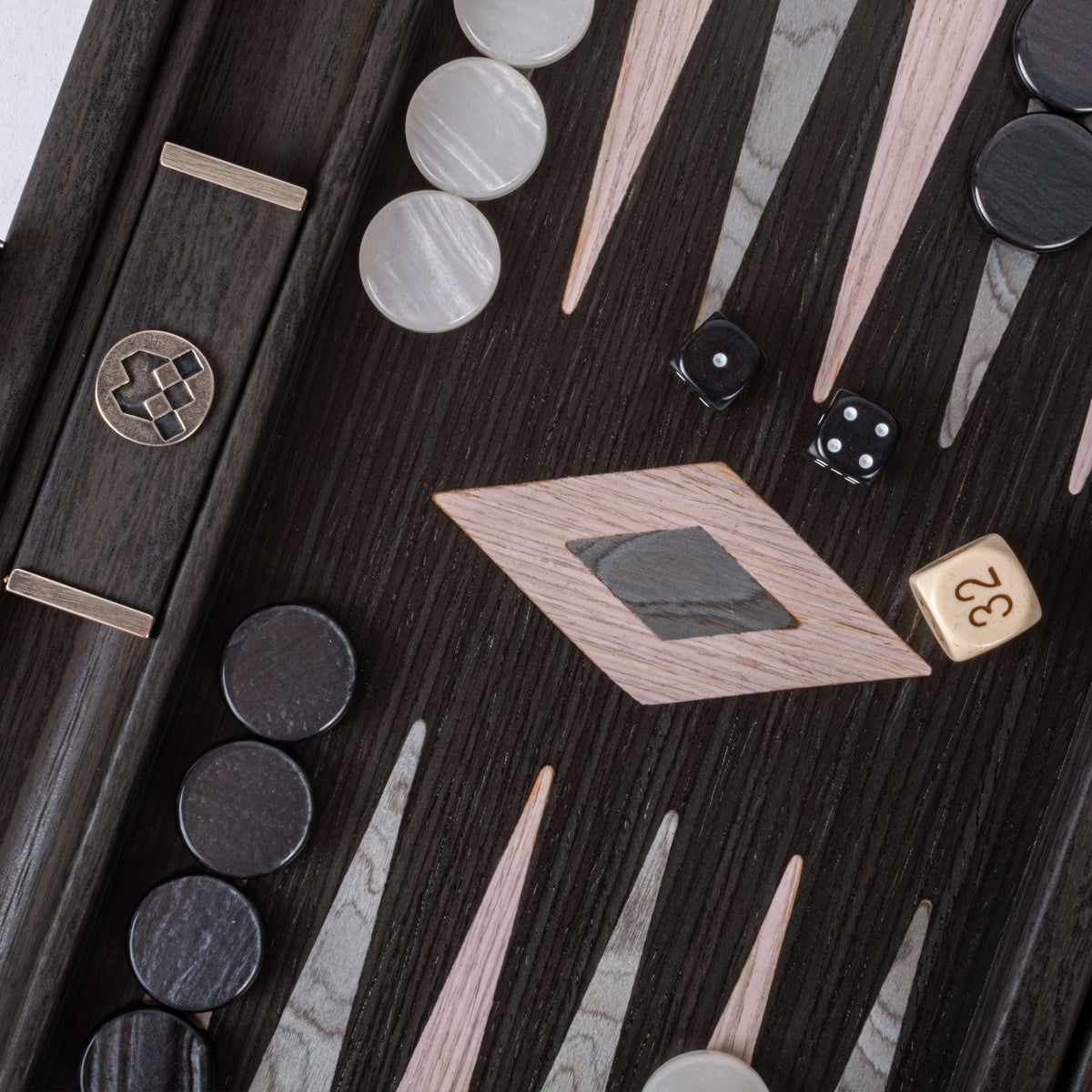 Close view of a luxury handcrafted backgammon board with dark wood grain pearly grey and black checkers dice and elegant geometric inlays by Manopoulos