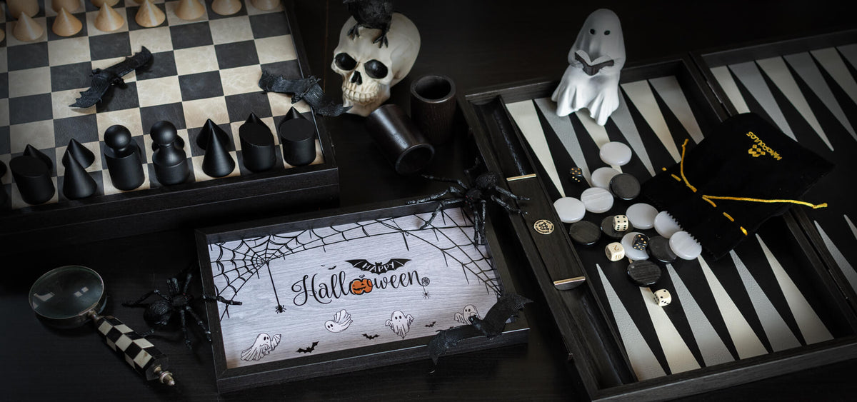 Halloween themed game display with black and white chess pieces, a skull, ghost figures, bats, dice, and a central board decorated with playful spooky illustrations1621243260e1af0c20-0